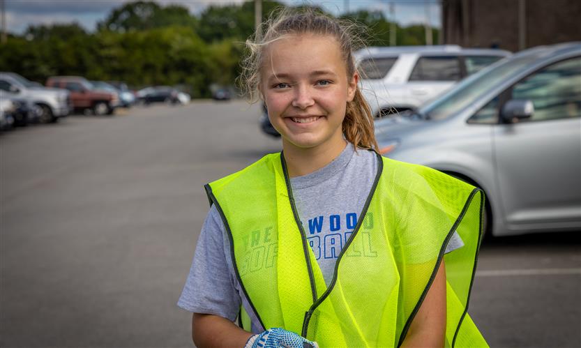 A girl smiles while wearing a neon vest